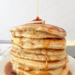 Stack of Vegan Pancakes on a white plate with syrup and butter