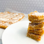 Apricot and Coconut Slice stacked up with a cut up slice in the background