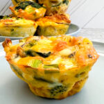 Broccoli and Red Onion Egg Muffins Cups on a blue plate with muffins in the background