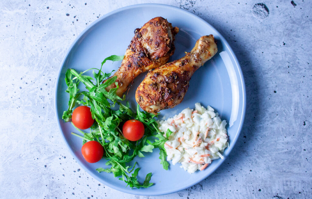 two Spiced Chicken Drumsticks and salad on a blue plate