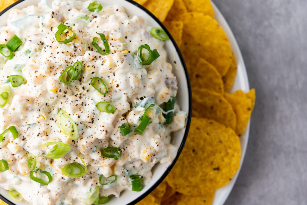 Corn Dip in a white bowl served with tortilla chips