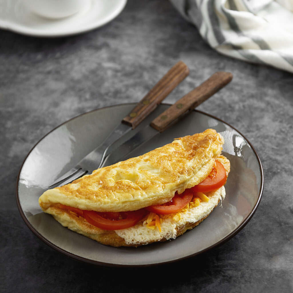 Omelet with cheese and tomatoes. Healthy homemade omelette for breakfast. Dark background.