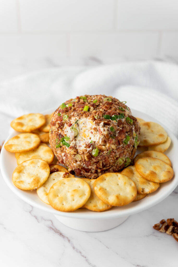 Pecan Bacon Cheeseball surrounded by crackers on a white plate