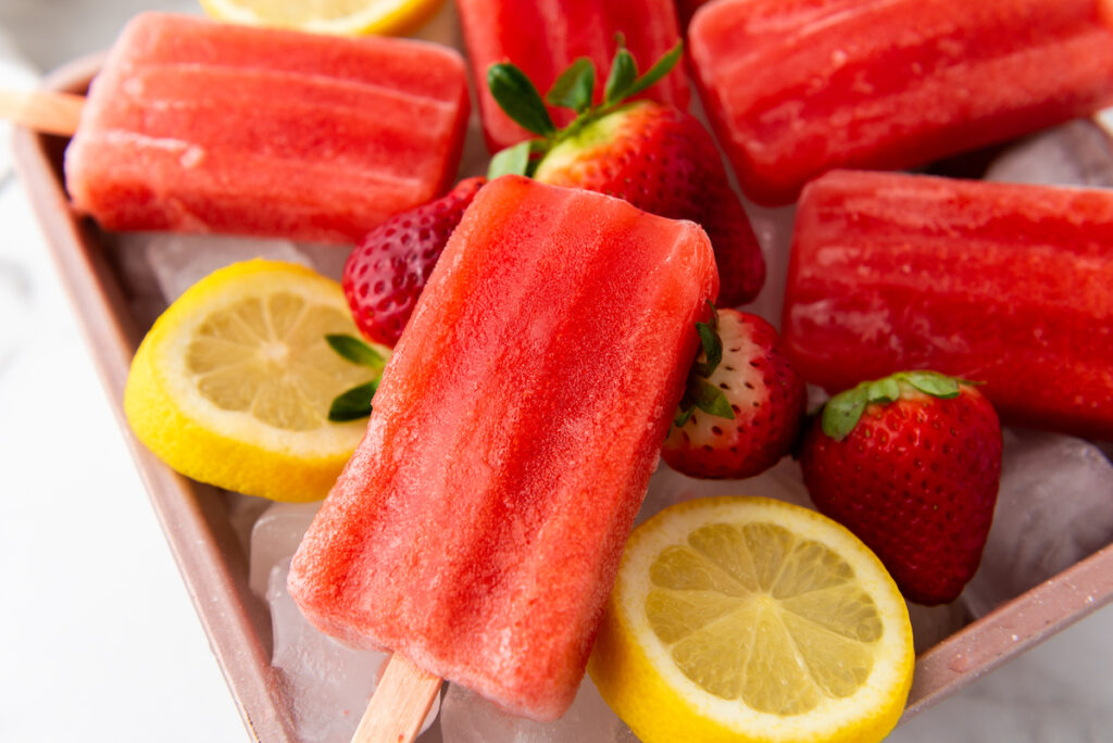 Strawberry Lemon Popsicles with slices of lemon and strawberries on ice