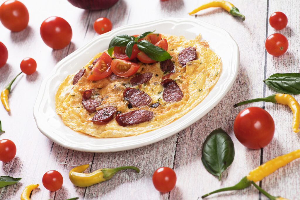 Omelet with pepperoni sausage, cherry tomato and basil served on a plate