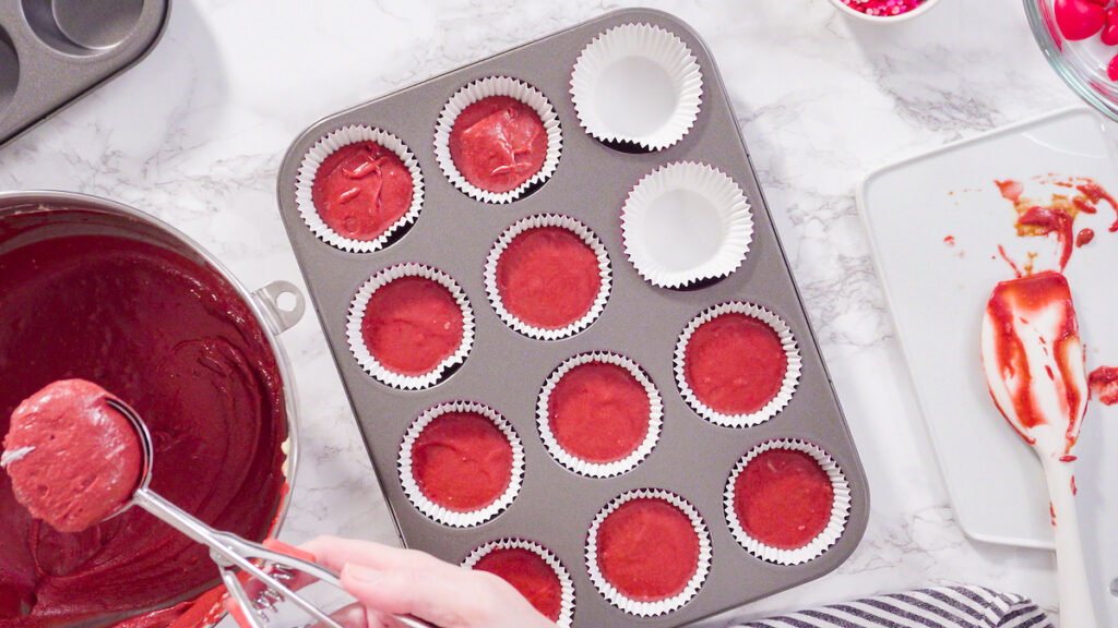 Flat lay. Step by step. Scooping cupcake batter into foil cupcake cups to bake red velvet cupcakes.